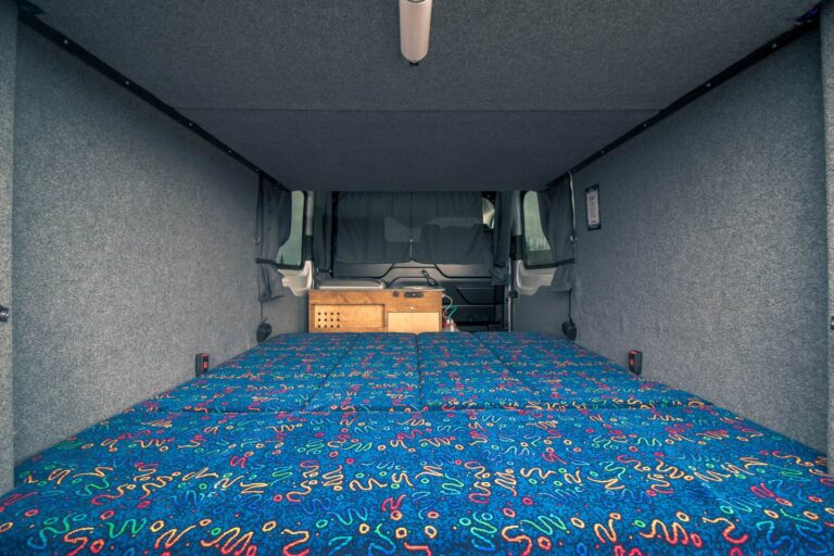View of the bed and kitchen corner inside the camper.