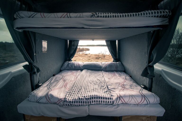 A set up bedding inside a campervan with opened back door.