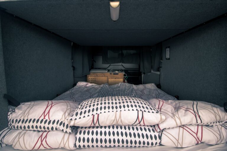 A interior of campervan showing the set up bedding and a kitchen corner in the back.