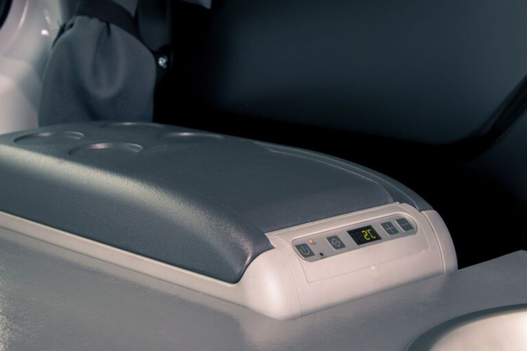 A grey fridge with buttons inside a campervan.
