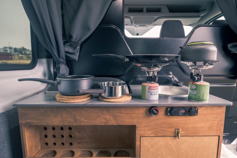 A kitchen corner in a campervan, displaying various pots and pans arranged on its surface