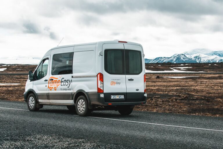 A campervan parked on the road with majestic mountains rising in the background in Iceland.
