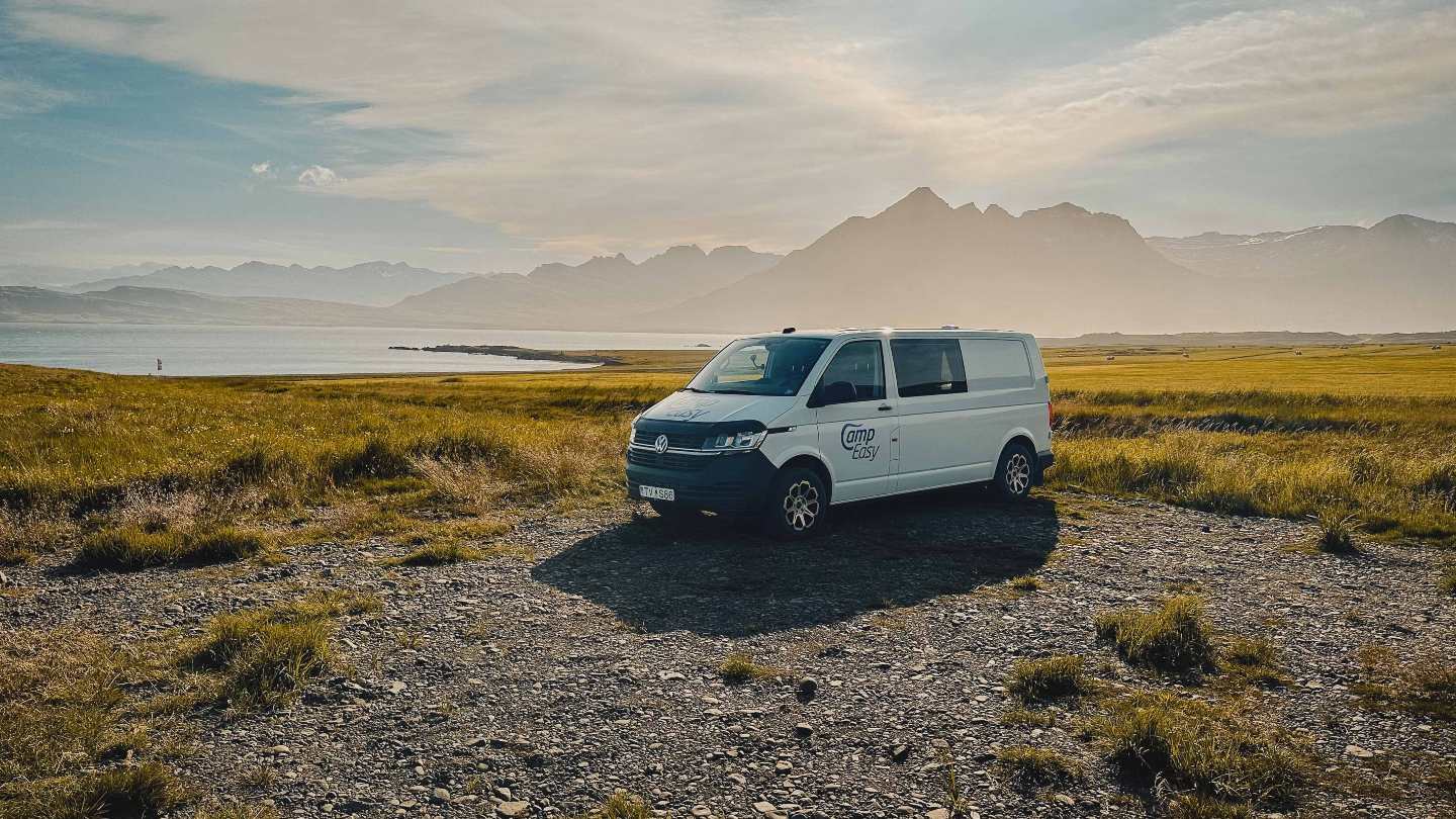 Campervan parked in Icelandic nature with scenic mountains and a lake in the background