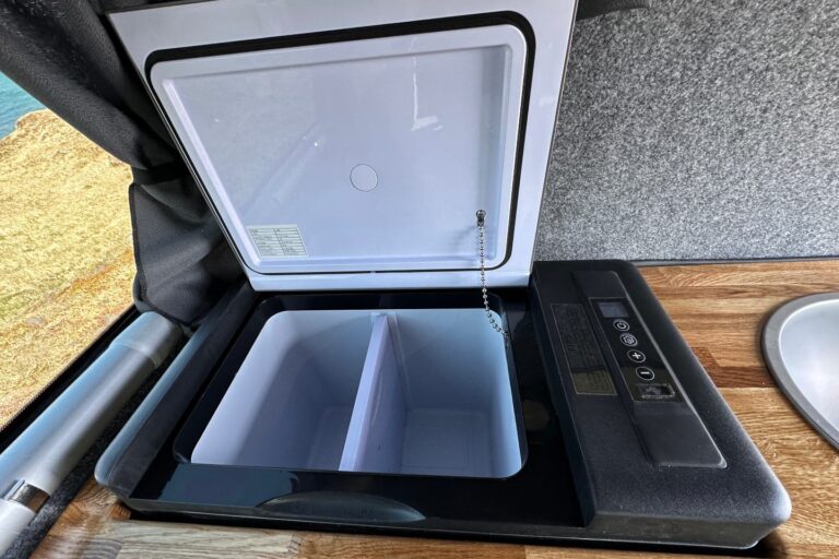 Opened fridge located in the kitchenette inside the campervan.