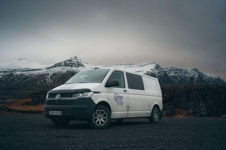 White 'Camp Easy' campervan parked on a road with snow-covered mountains in the background.