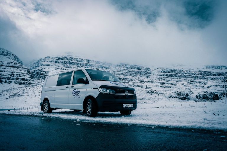White 'Camp Easy' campervan parked on a snowy road with misty mountains in the background.