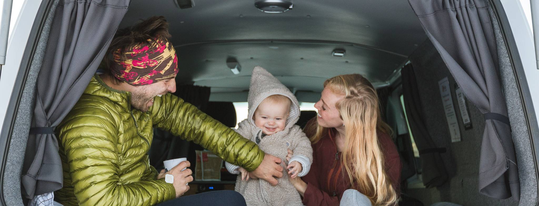 Family of three are on the bed inside the campervan enjoying their time.