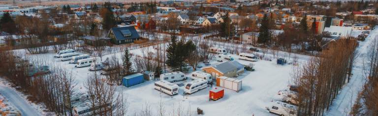 View of a snow-covered campground with camping trailers.
