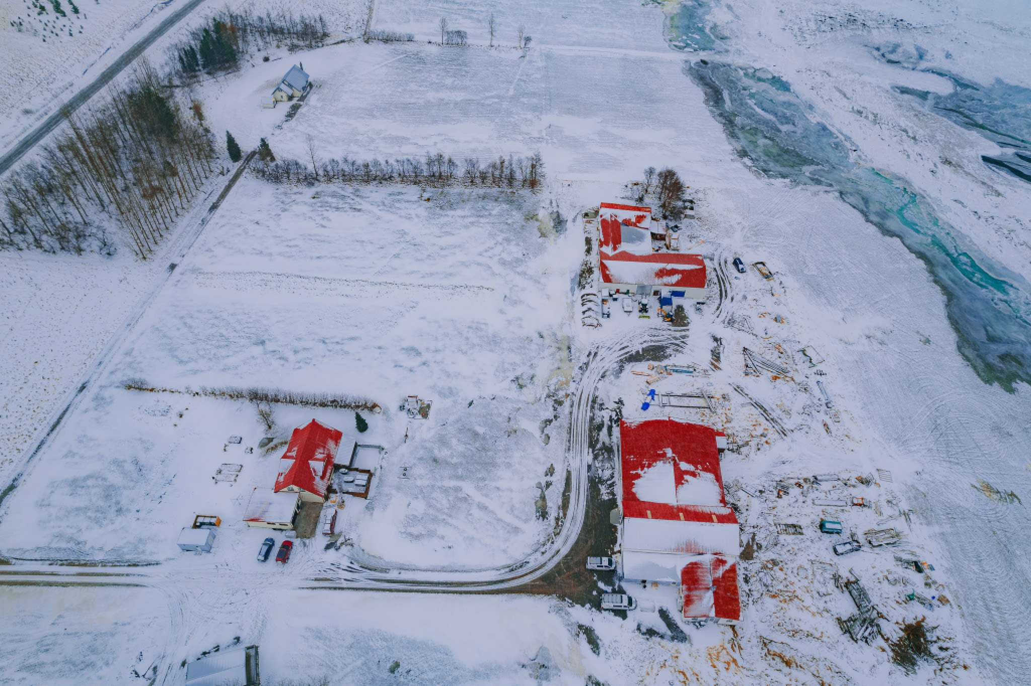 Aerial view of a snowy landscape featuring several buildings with red roofs and winding roads.