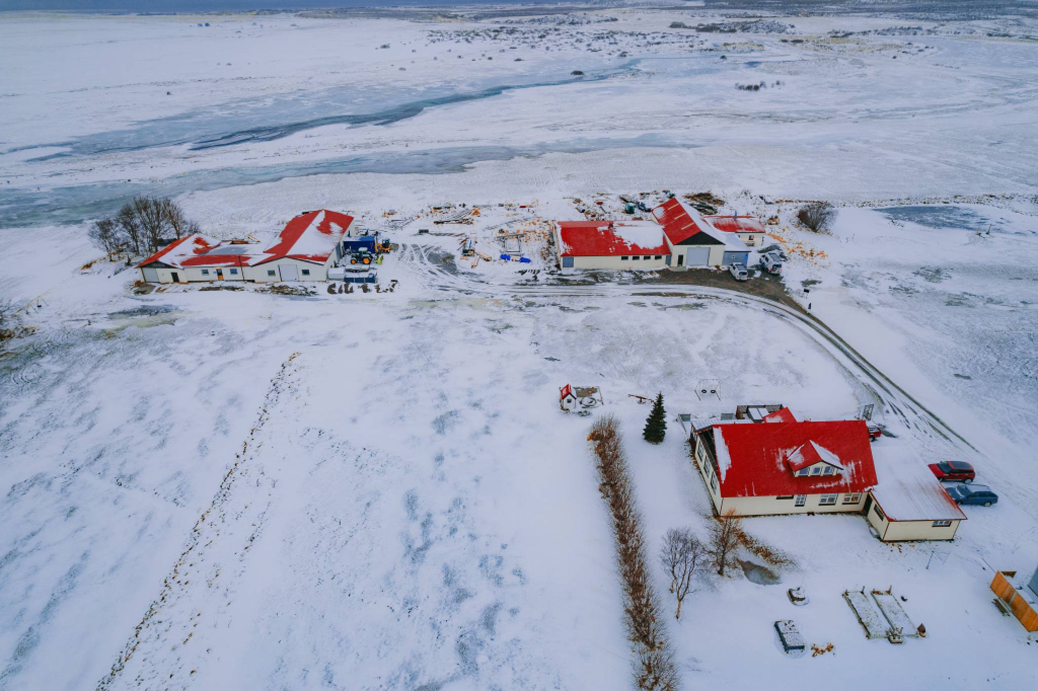 Aerial view of snow-covered landscape with scattered buildings featuring bright red roofs.
