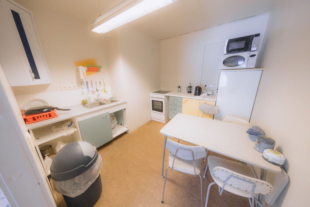 Compact kitchen with a white table and three chairs, stove, and a microwave.