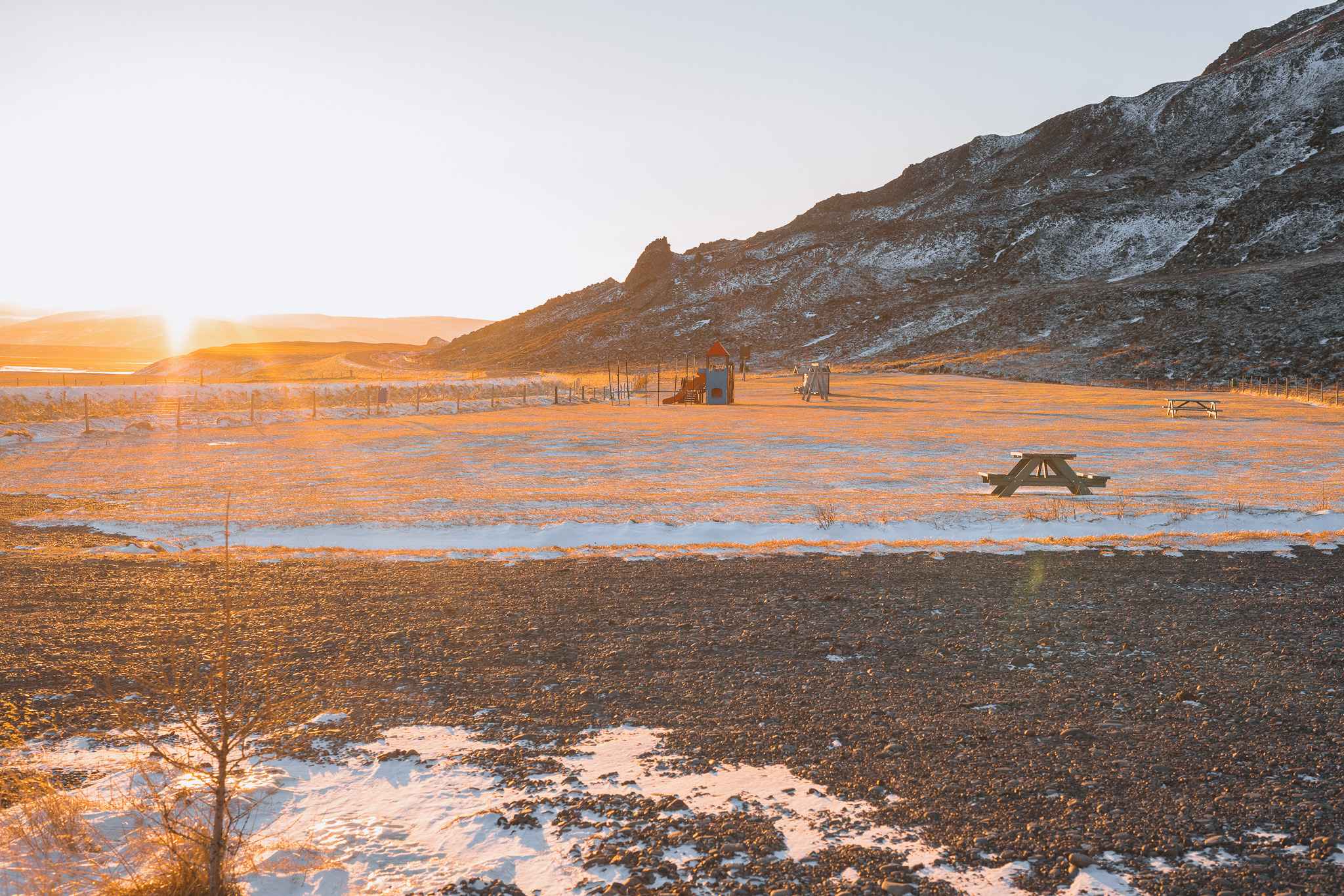Sunset over a snowy playground with distant mountains.
