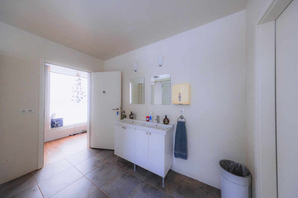 Minimalist bathroom with a double sink vanity, two mirrors, and a towel hanging on the wall.