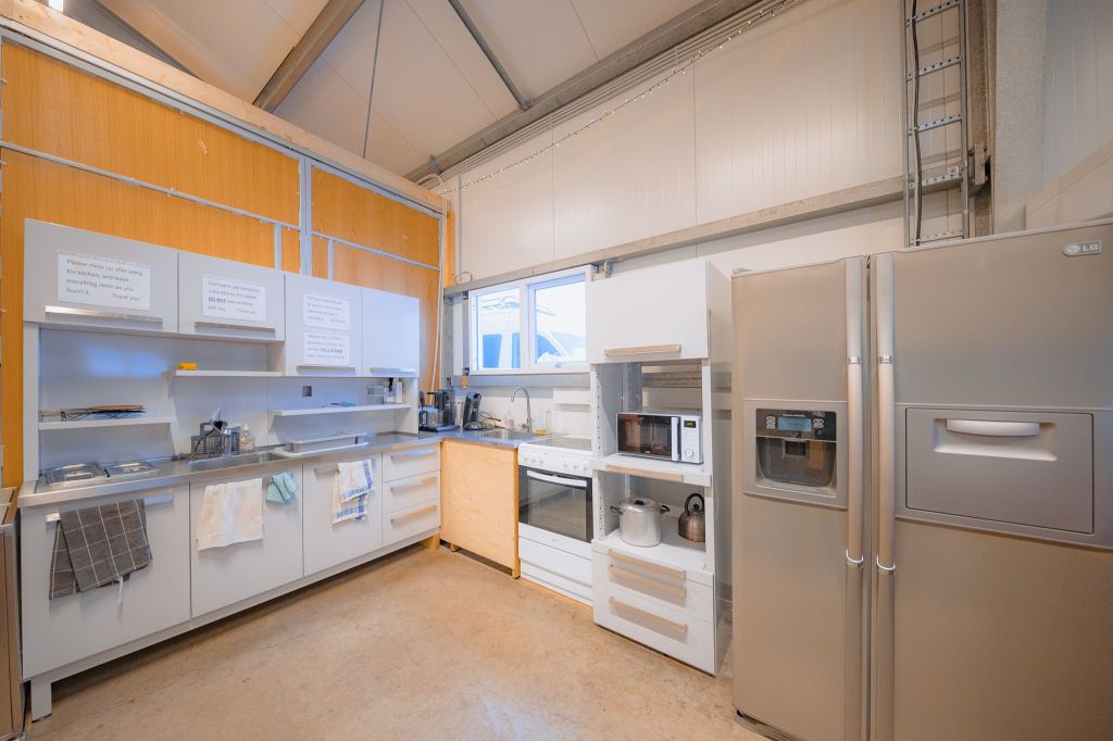 Modern kitchen with light wood accents, featuring stainless steel appliances, including a fridge and stove.
