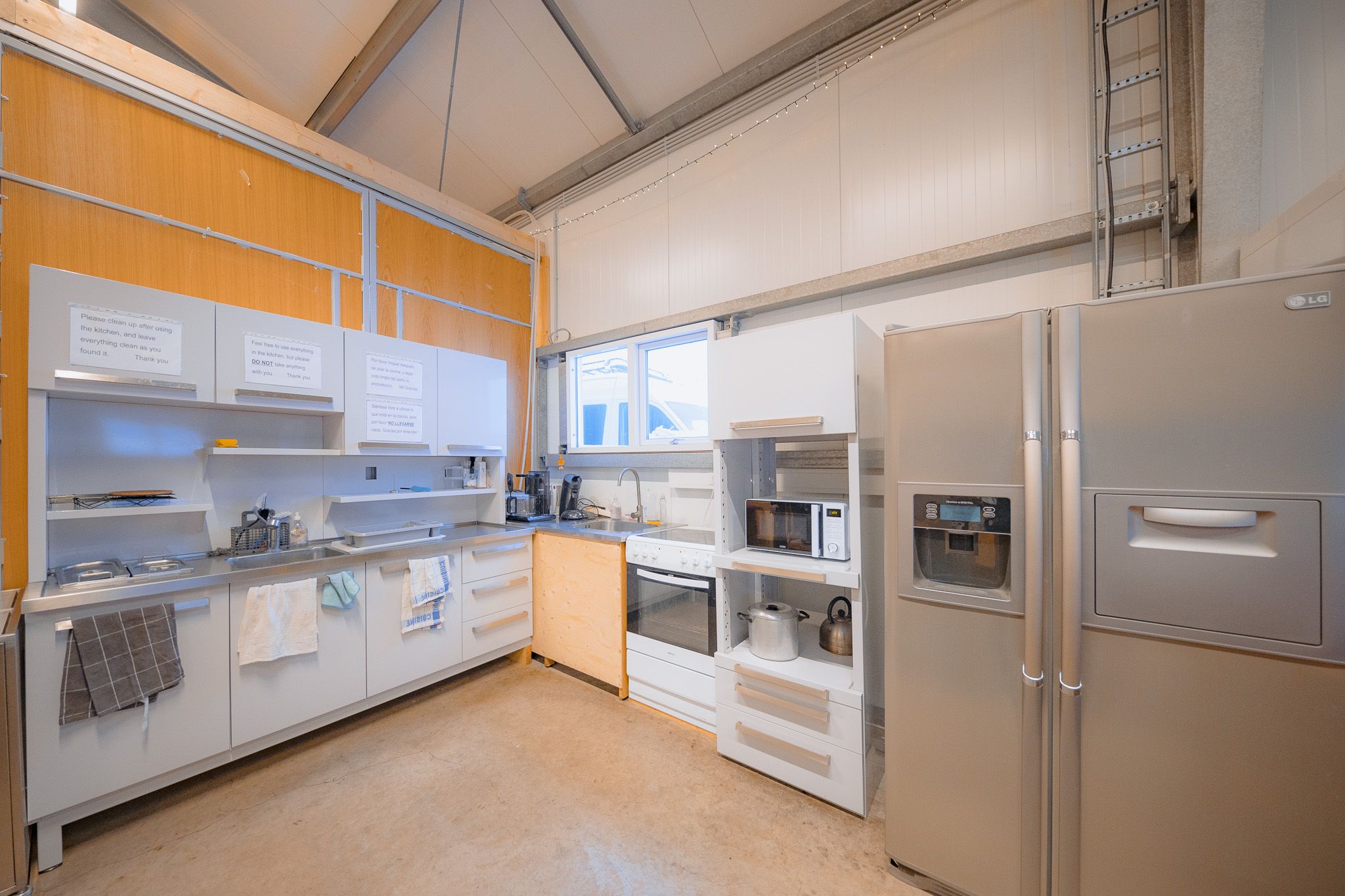 Modern kitchen with light wood accents, featuring stainless steel appliances, including a fridge and stove.