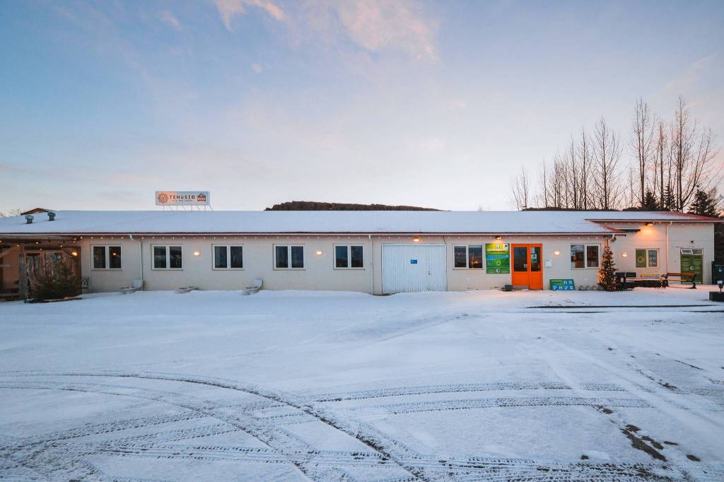 A long, single-story building with Christmas decorations and a light dusting of snow. The sky is pale with hints of orange from a setting or rising sun.
