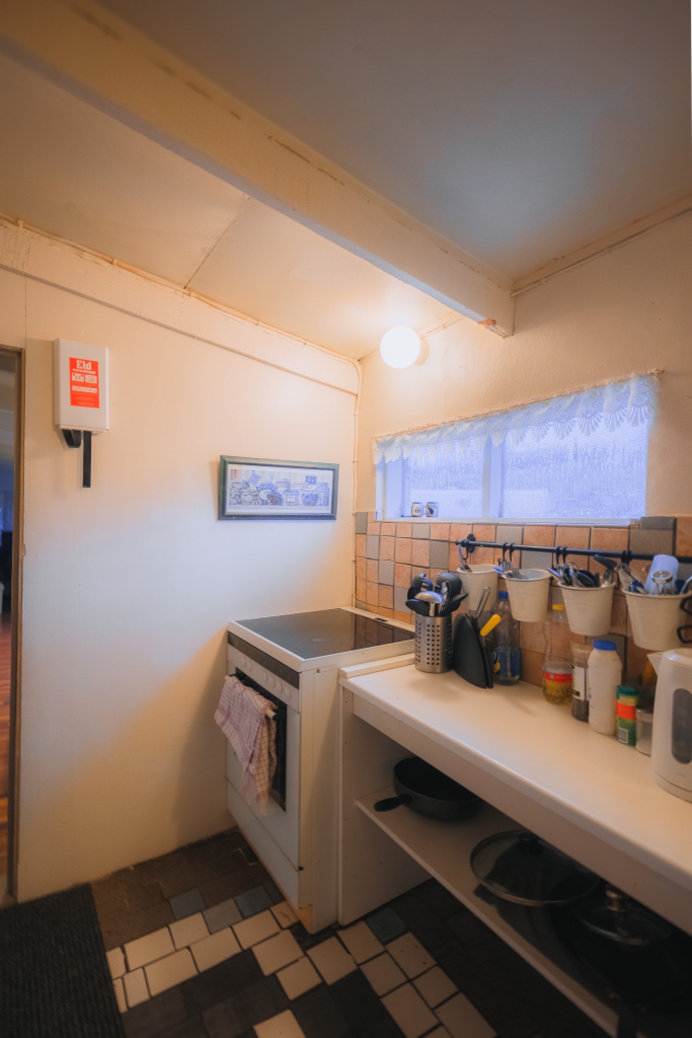 Cozy kitchen corner with a stove and wall-mounted utensils. Soft lighting casts a warm glow on the textured walls and patterned floor tiles.