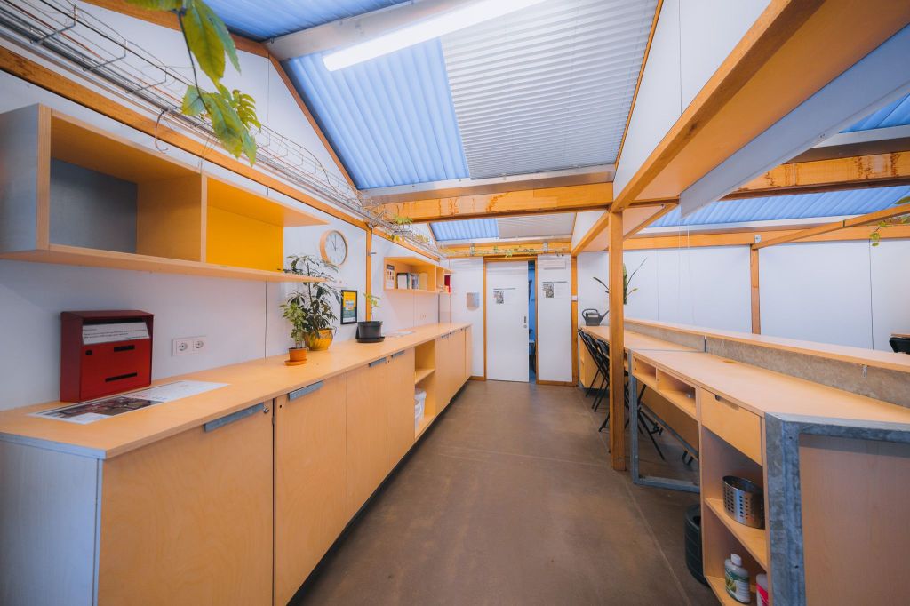 Spacious, modern room with wooden shelves and counters, vibrant plant decor, a red mailbox, and bright lighting.