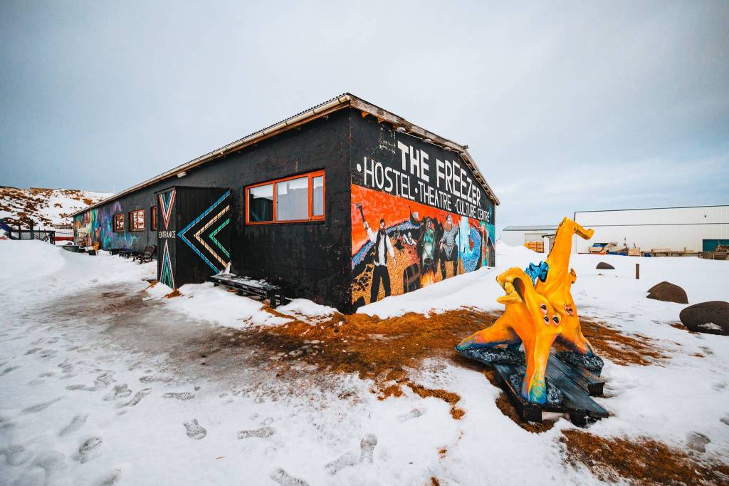 A colorful, snowy scene of "The Freezer" hostel with bright murals on the walls.
