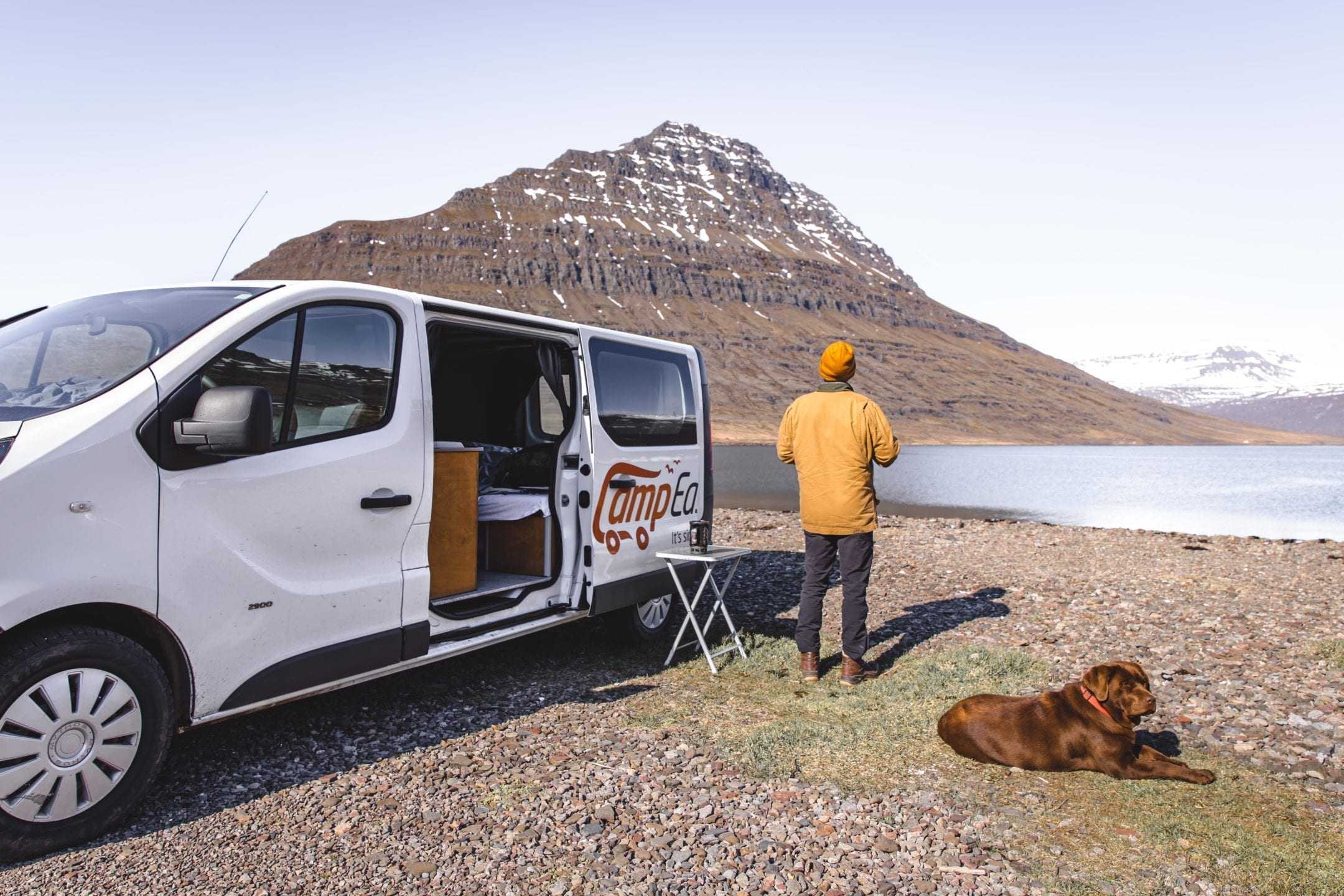 Man and a dog standing next to a camper